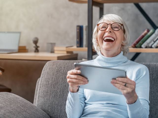 Woman laughing while watching a family video on a tablet